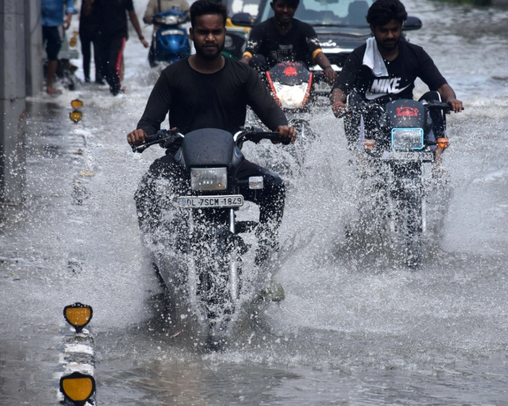 Commuters wading through a waterlogged road at ITO, in New Delhi