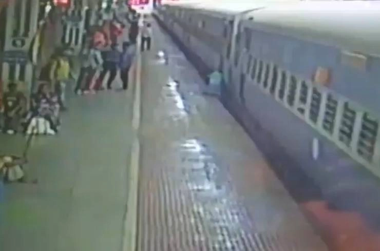 चलती ट्रेन पर चढ़ते हुए फिसल गया हाथ, नीचे गिरा ‍पर बच गई जान, वायरल हुआ वीडियो - A man survives after he fell on the tracks from running train