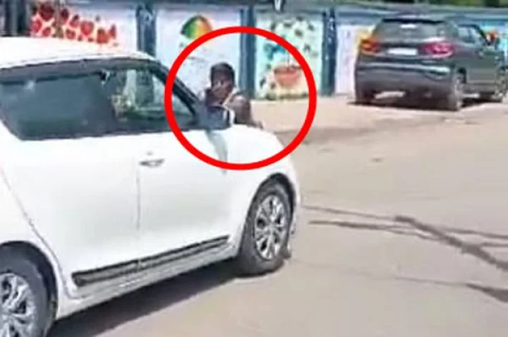 Woman hanging on the bonnet of a moving car
