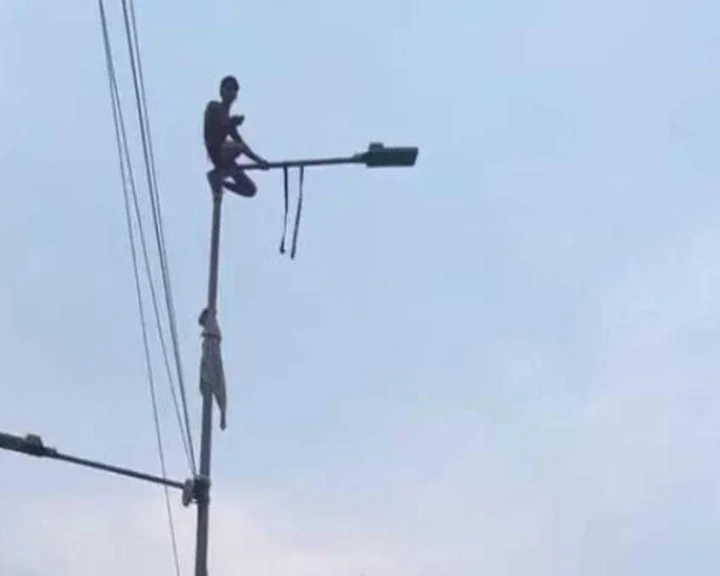 Man climbs light pole
